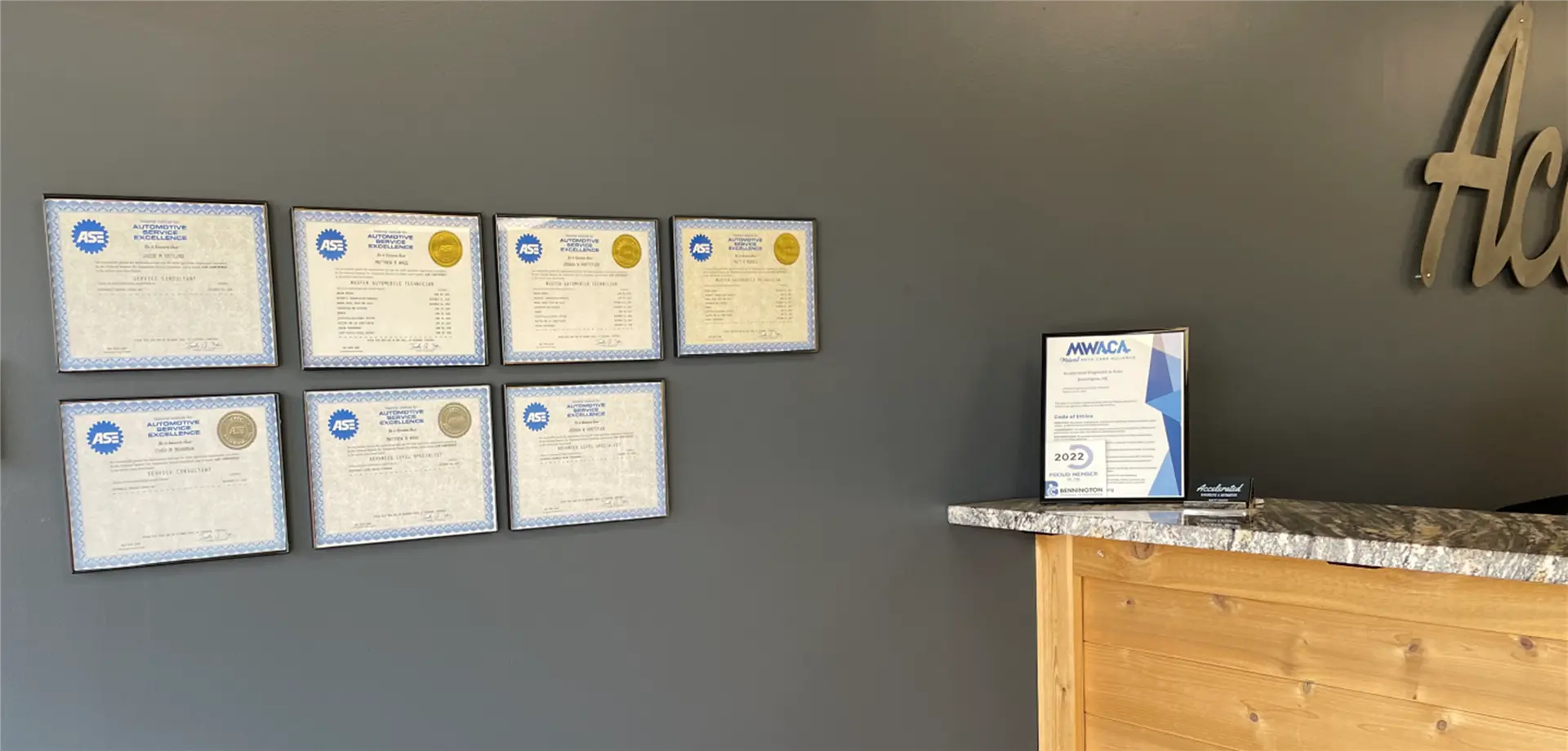 Automotive repair shop reception area displaying ASE certifications and industry awards mounted on a wall behind the counter.