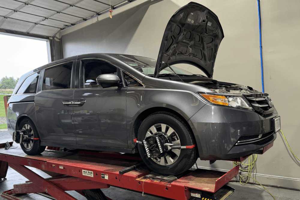 Wheel alignment, auto repair in Bennington, NE, at Accelerated Diagnostic and Automotive. Image of Honda Odyssey minivan on an alignment rack with wheel alignment sensors attached, illustrating the relationship between wheel alignment and ADAS calibration services at an automotive repair shop.